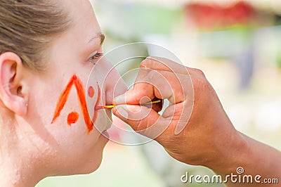 CUYABENO, ECUADOR- MAY 06, 2017: Unidentified tourist painting her face using achiote seeds from these spiny red pods Editorial Stock Photo