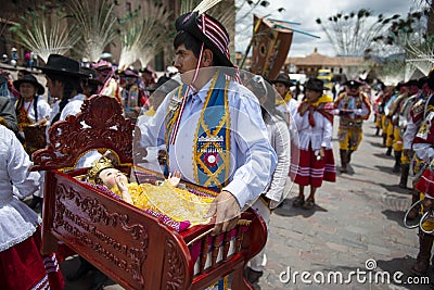 A man holding a cradle with baby Jesus and wearing traditional clothes during the Huaylia on Christmas day at the Plaza de Armas s Editorial Stock Photo