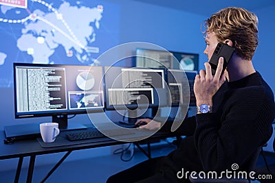 Cyber Security Control Center Operator in Phone Call Working. Multiple Screens Showing Technical Data and Alerts. Stock Photo