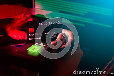 Cybercrime concepts The hacker& x27;s hand is holding a credit card with a blurry computer background. Stolen data and use it for Stock Photo