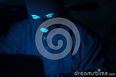Cybercrime, hacking and technology crime. Masked hacker working in the darkness stealing data and personal identity information Stock Photo