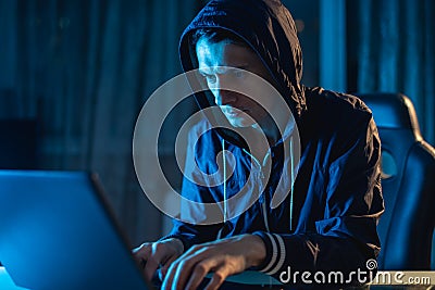 Cybercriminal hacker in the hood typing program code while stealing access databases with passwords. Cyber security Stock Photo