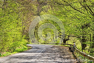 Cycle ride. Spring cycling. Green trees and grass around. Outdoor activities. The guy stopped to rest. A road with falling shadows Stock Photo