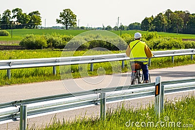 Cycling outdoor â€“ elderly woman in a yellow vest riding a bicycle Stock Photo