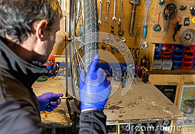 Cycle mechanist working on spokes on wheel in workshop Stock Photo