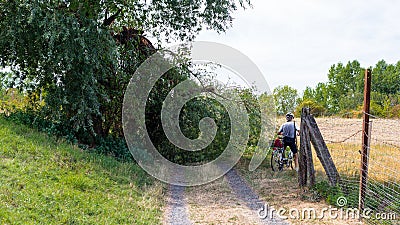 Cyclist avoiding a fallen tree from a strong wind lying on a dirt road in a field in western Germany. Editorial Stock Photo