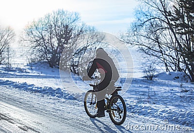 Cyclist on a bike rides in the winter on road Stock Photo