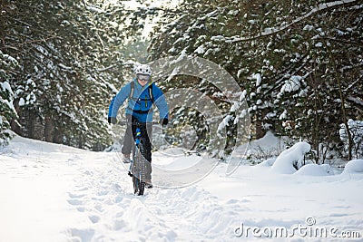 Cyclist in Blue Riding the Mountain Bike in Beautiful Winter Forest. Extreme Sport and Enduro Biking Concept. Stock Photo