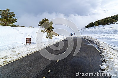 cyclist climbing snowy high mountain pass. La Morcuera Stock Photo