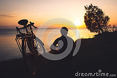 Cyclist enjoy panoramic view of lake outdoors on sunset. Healthy lifestyle and bicycle touring. Ecological travel Stock Photo