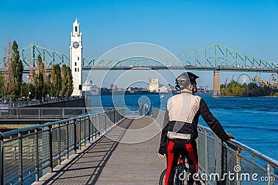 Cyclist looking at the Saint-Lawrence River, with Clock Tower and Jacques Cartier Bridge in background Editorial Stock Photo