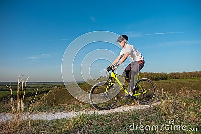 A cyclist in an orange hoodie rides a bike along a mountain path. The concept of extreme sports. Stock Photo