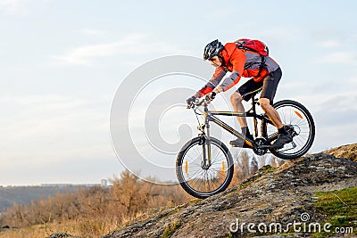 Cyclist in Red Jacket Riding the Bike Down Rocky Hill. Extreme Sport. Stock Photo