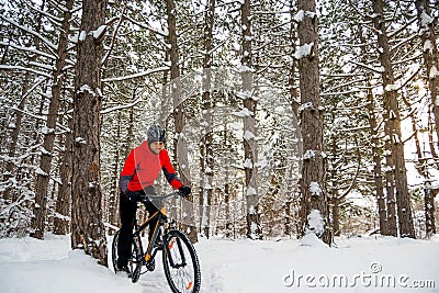 Cyclist in Red Riding Mountain Bike in Beautiful Winter Forest. Adventure, Sport and Enduro Cycling Concept. Stock Photo