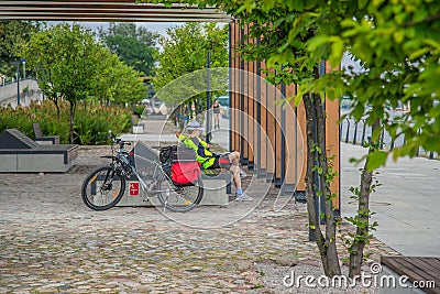 Cyclist resting on a bench on a walkway Editorial Stock Photo