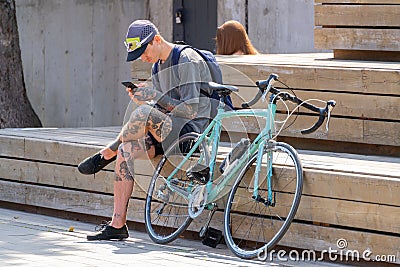 cyclist resting next to a bicycle on a city street Editorial Stock Photo