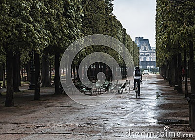 A cyclist rides through the park in Paris after the rain Editorial Stock Photo
