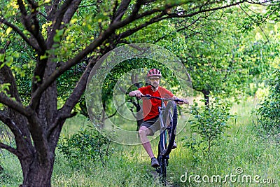 A cyclist rides on the rear wheel of a bicycle along a forest path. Active lifestyle, extreme Stock Photo