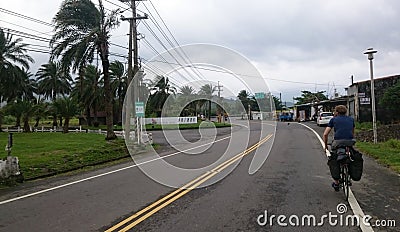 Cyclist riding his bike down the road, wind Blows the Palm trees Editorial Stock Photo