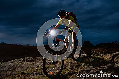 Cyclist Riding the Mountain Bike on Rocky Trail at Night. Extreme Sport and Enduro Biking Concept. Stock Photo