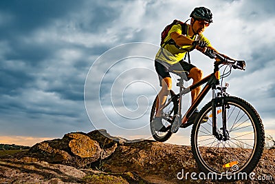 Cyclist Riding the Mountain Bike on Rocky Trail at Sunset. Extreme Sport and Enduro Biking Concept. Stock Photo