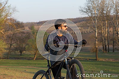 Cyclist in shorts and jersey on a modern carbon hardtail bike with an air suspension fork standing on a cliff against the backgrou Stock Photo