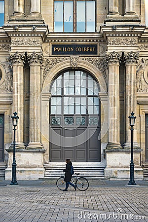 Cyclist walking in front the Pavillon Colbert of the Louvre museum, Paris, France Editorial Stock Photo