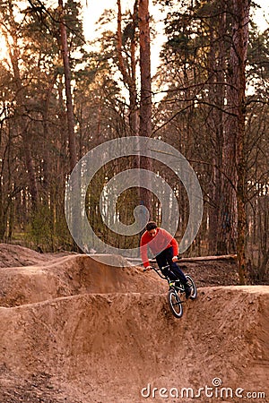 Cyclists in the forest on a track with slides for sport mountain Biking. Mountain bike jumping, extr Editorial Stock Photo