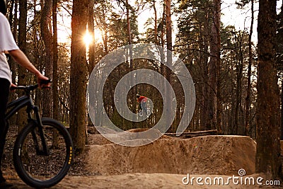 Cyclists in the forest on a track with slides for sport mountain Biking. Mountain bike jumping, extr Editorial Stock Photo