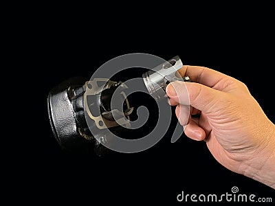 Cylinder and piston in a hand, on a black background. Piston system from a moped. Parts of a motor from a motorcycle, closeup Stock Photo