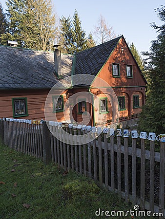 Czech Republic, Vlci Hora, November 30, 2019: Beautiful orange green wooden timbered house or cottage with fence covered Editorial Stock Photo