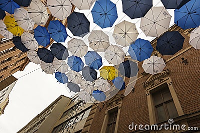 Czech street in Brno. view upwards, between tall houses hanging on a rope colored umbrellas in yellow, blue, white Editorial Stock Photo