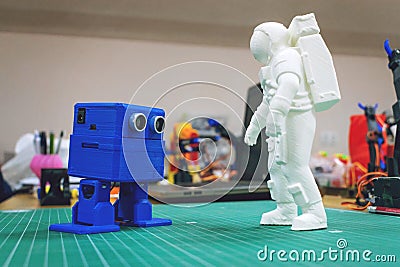 3D printed astronaut, cosmonaut and cute robot on the background of devices and laptop. Stock Photo