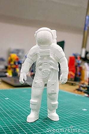 3D printed astronaut, cosmonaut, robot on the background of devices and laptop. Spaceman model printed on automatic three Stock Photo