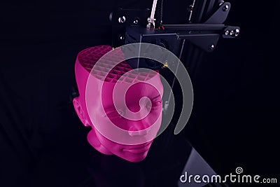 A 3D printer produces a futuristic sculptural humanoid head from pink plastic in foggy light. Stock Photo