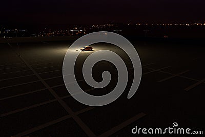 A single car in a parking lot representing the concept of working late Stock Photo