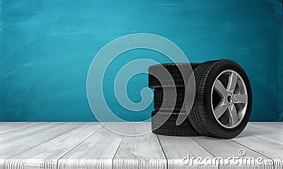 3d rendering of a single car tire leaning on three tires standing on a wooden surface in front of blue background. Stock Photo