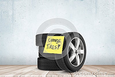 3d rendering of stack of black tires with yellow post-it note saying `Change Tires`, against concrete wall on wooden Stock Photo