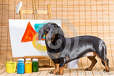 Dachshund artist near easel with its masterpiece Stock Photo