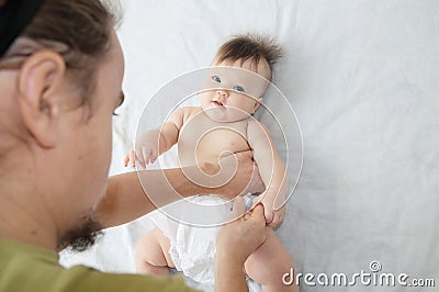 Dad changing diaper on baby girl on bed, changing nappy, everyday life Stock Photo