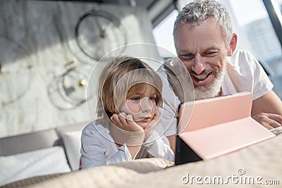 Dad and child communicating looking together tablet Stock Photo