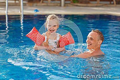 Dad and daughter swim in the pool, and she laughs out loud and s Stock Photo