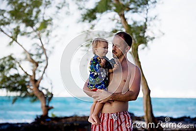 Dad, holding little toddler boy with binoculars, observing dolphins Stock Photo