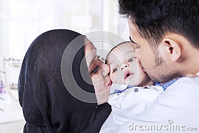 Dad and mom kissing baby cheeks Stock Photo