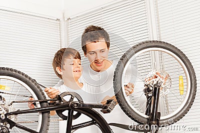 Dad showing his kid son how to repair bicycle Stock Photo