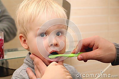Dad and son brush their teeth in the bathroom. Father Brushing Teeth to Child Stock Photo