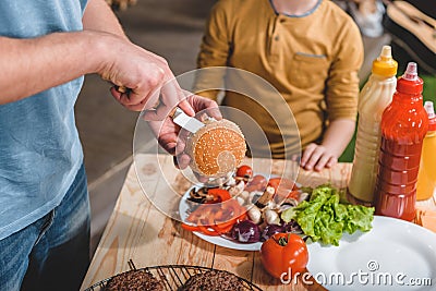 Dad and son cooking meat burgers together Stock Photo