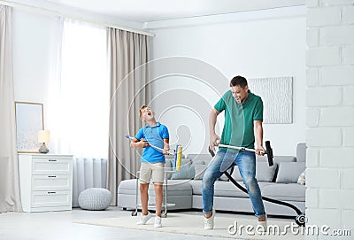 Dad and son having fun while cleaning living room Stock Photo