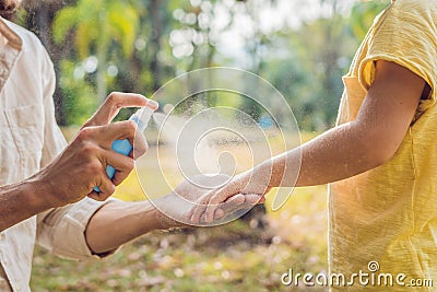 Dad and son use mosquito spray.Spraying insect repellent on skin outdoor Stock Photo