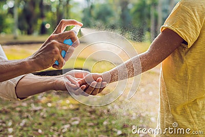 Dad and son use mosquito spray.Spraying insect repellent on skin outdoor Stock Photo